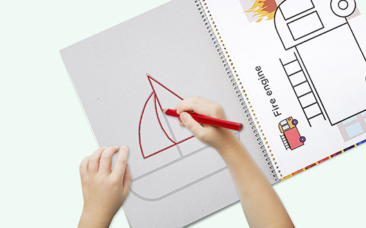 La mano de un niño dibujando un velero mientras toca el braille