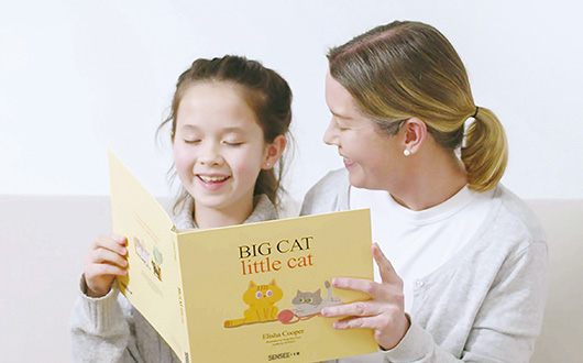 엄마와 딸이 센시 점자책을 함께 읽으며 웃고 있다.